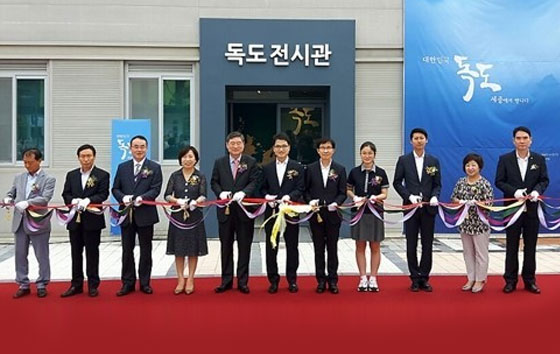 독도전시관 개관행사에서 여러 사람들이 줄을 자르고 있음