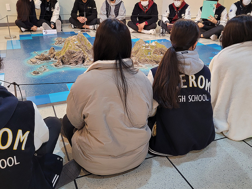 독도체험관에서 단체 전시 해설을 듣는 학생들